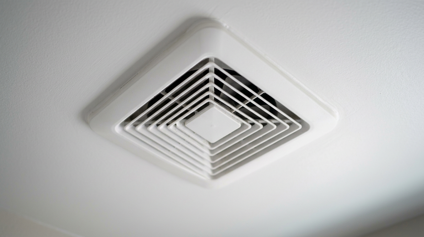 A close-up of a clean, modern bathroom exhaust fan on a ceiling, illustrating mold prevention in a Newcastle, WA home.